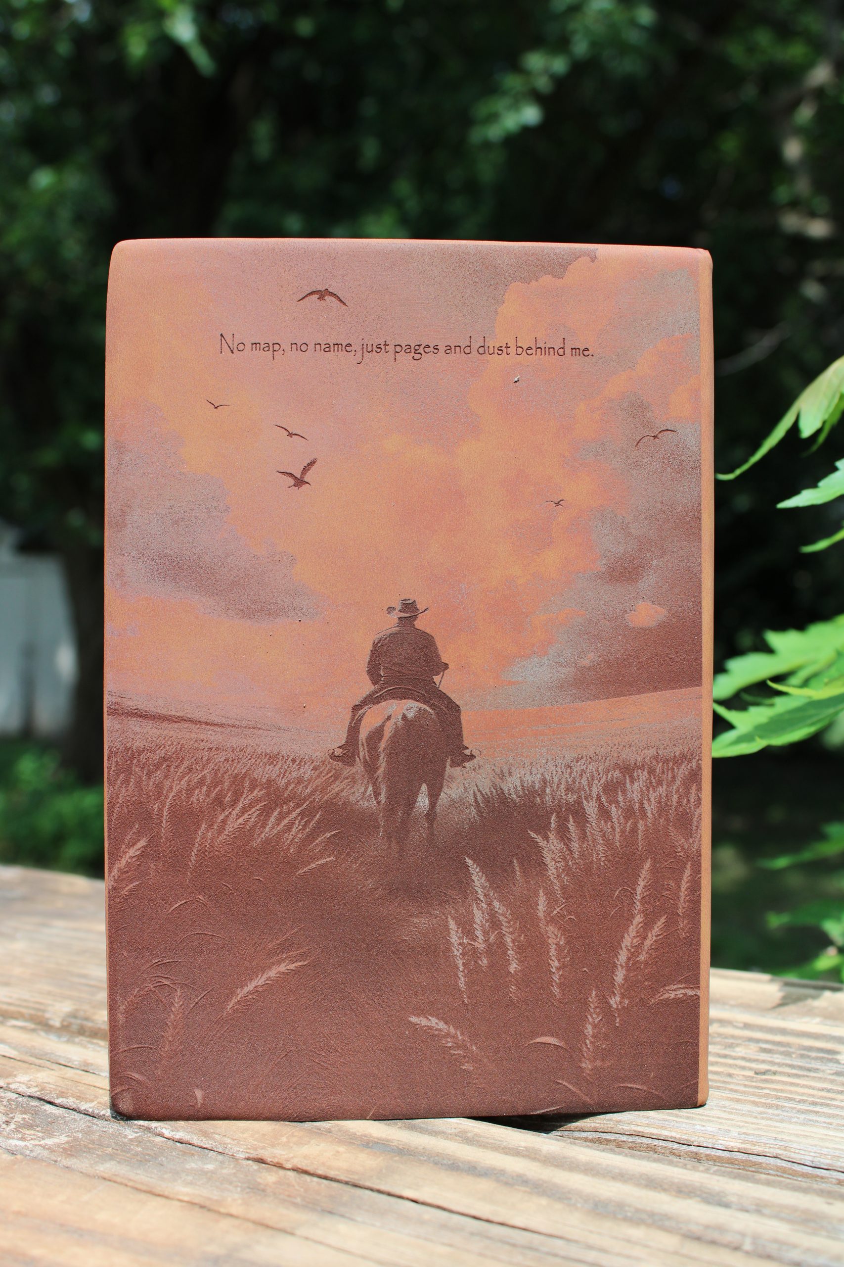 a brown journal picturing a cowboy riding a horse off into the sunset